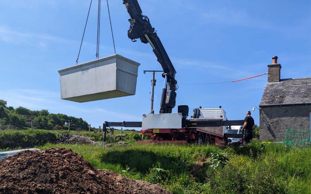 A septic tank being lifted by a crane in an installation