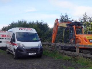 A van and a digger installing a new tank.