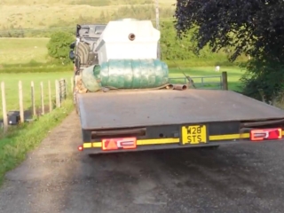 New sewage treatment tank on a truck going down a windy road.